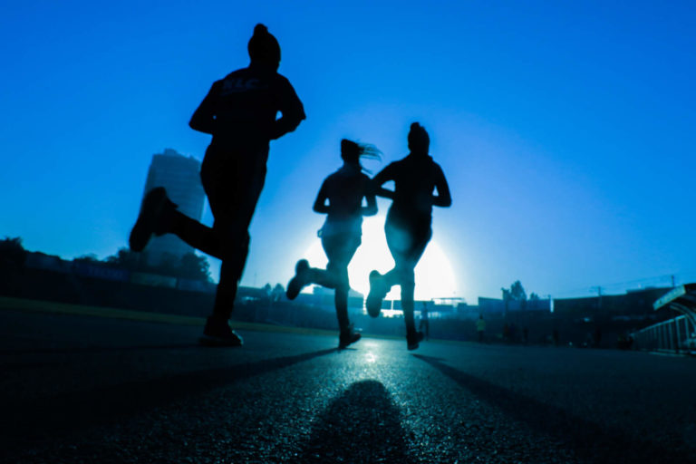 Silhouette of three people running.