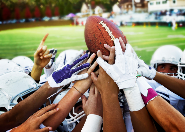A group of football players holding a football.