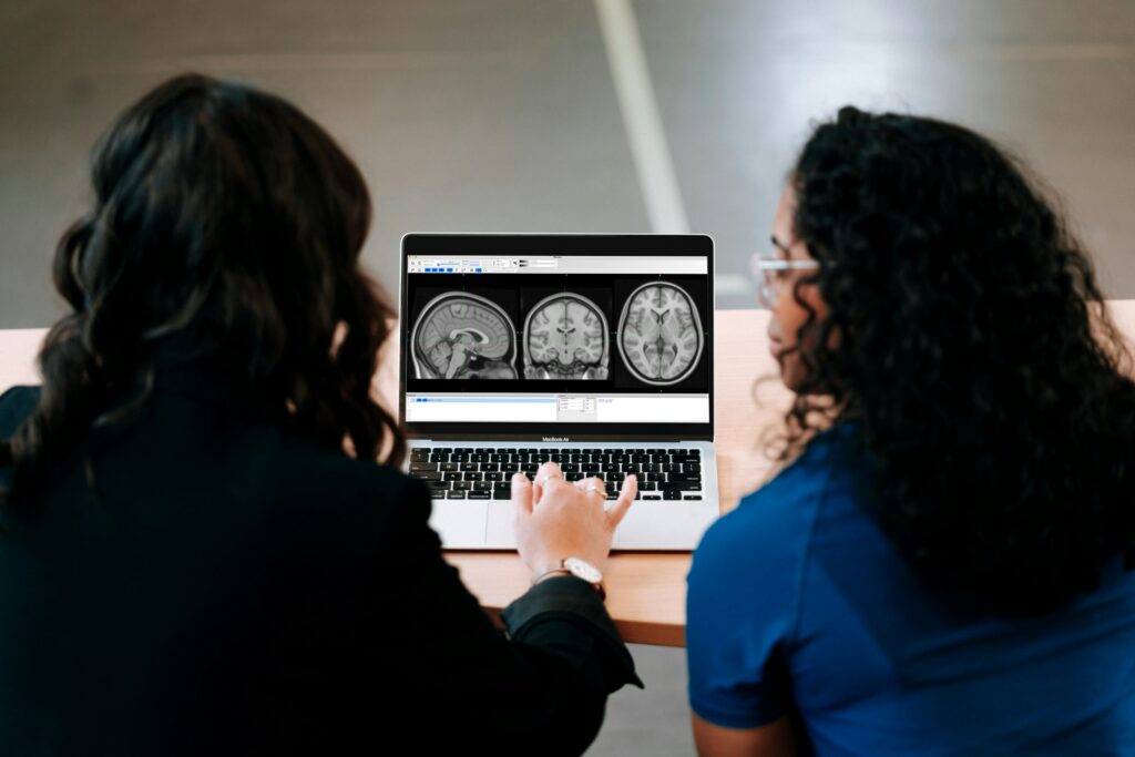 Two people observing brain scans on a laptop.